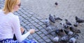 Group doves on city square waiting treats. Girl feeding dove birds urban background. Girl blonde woman relaxing city