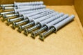 Group of dowels and nails on the bottom of cardboard box. Storage of materials for repair. Dowels for fixing to concrete. Royalty Free Stock Photo