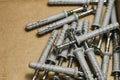 Group of dowels and nails on the bottom of cardboard box. Storage of materials for repair. Dowels for fixing to concrete. Royalty Free Stock Photo