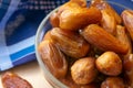 Group of dried sweet deglet nour date fruites in translucent bowl and dark blue napkin