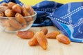 Group of dried sweet deglet nour date fruites in translucent bowl and dark blue napkin