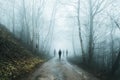A group of eerie ghostly figures emerging from the fog on a spooky forest road in winter. With a high contrast photoshop edit