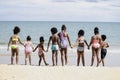 Group of eight boys and girls holding hands in a line running to sea water, cute kids having fun on sandy summer beach, happy Royalty Free Stock Photo