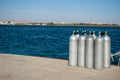 Group eight cylinders with air. eight aluminum cylinders on sea dock. Blue ocean and white steel cylinders