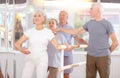 Group of elderly dancers engaged in ballet in dance studio perfoms exercise near ballet barre, senior male choreographer Royalty Free Stock Photo