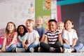 Group Of Elementary School Pupils Sitting On Floor In Classroom