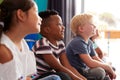 Group Of Elementary School Pupils Sitting On Floor Listening To Teacher