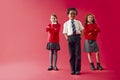 Group Of Elementary School Pupils Wearing Uniform Folding Arms Against Red Studio Background Royalty Free Stock Photo