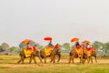 A group of elephant riding stands in front of the very old big p