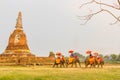 A group of elephant riding stands in front of the very old big p