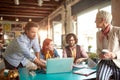 Group of employees is discussing laptop content while working in the office together