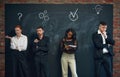 Group of employees standing by blackboard with drawn business icons, working on projects, generating ideas and fixing Royalty Free Stock Photo