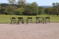 A group of empty chairs and tables on the edge of a gravel courtyard