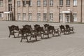 Group of empty vintage wooden benches with ornate black iron forged elements in small provincial town in sepia tone. Royalty Free Stock Photo