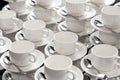 A group of empty white cups and saucers with a teaspoon. Many rows of white cups of tea for serving for breakfast or buffet Royalty Free Stock Photo