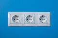 Group of empty white electrical european outlet located on blue wall - close up Royalty Free Stock Photo