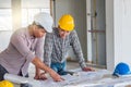 Group of engineer checking the blueprint on the table and talking about construction project with commitment to success at Royalty Free Stock Photo