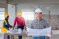 Group of engineer checking the blueprint on the table and talking about construction project with commitment to success at Royalty Free Stock Photo