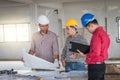 Group of engineer checking the blueprint on the table and talking about construction project with commitment to success at Royalty Free Stock Photo