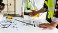 A group of engineers and architects are discussing the construction of the building. With blueprints on the desk in the constructi Royalty Free Stock Photo