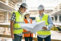 Group of engineers, builders, architects on the building site, looking in blueprint. Construction, development, teamwork and Royalty Free Stock Photo