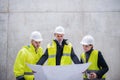 A group of engineers standing against concrete wall on construction site.