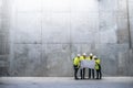 A group of engineers standing against concrete wall on construction site.