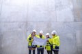 A group of engineers standing against concrete wall on construction site.