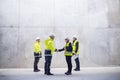 A group of engineers standing on construction site, shaking hands.