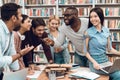 Group of ethnic multicultural students discussing studying in library.