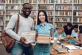 Group of ethnic multicultural students in library. Black guy and asial girl with books.