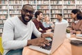 Group of ethnic multicultural students in library. Black guy on laptop. Royalty Free Stock Photo