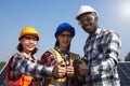 A group of ethnically diverse electrical engineers was thumbs up to show unity with the solar panel