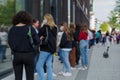 Group of European women with protective face mask queue and wait for shopping on sidewalk outside store during lockdown.