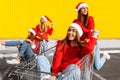 Group of excited, happy friends, young women in Christmas sweaters and Santa Claus hats, walking on city street, rolling on Royalty Free Stock Photo