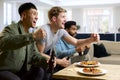 Group Of Excited Male Friends Watching Sports On TV At Home In Lounge With Pizza Together Royalty Free Stock Photo