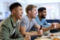 Group Of Excited Male Friends Watching Sports On TV At Home In Lounge Together Royalty Free Stock Photo