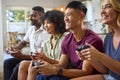 Group Of Excited Multi-Racial Friends Sitting On Sofa Playing Computer Games Together Royalty Free Stock Photo