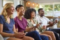 Group Of Excited Multi-Racial Friends Sitting On Sofa Playing Computer Games Together Royalty Free Stock Photo