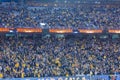 Group of excited soccer fans gathered in a stadium, cheering and watching a match