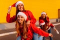 Group of excited young women wearing santa claus hats have fun and ride each other in the fresh air. New Year Royalty Free Stock Photo