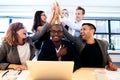 Group of executives high fiving over colleague's head