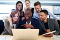 Group of executives smiling gathered around laptop