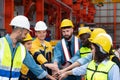 Group of factory workers in hardhats with joint hands together
