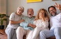 Group of family relaxing on sofa at home having fun and laughing. Handsome  people, parents and adult sons, two generations Royalty Free Stock Photo