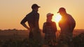 A group of farmers are discussing in the field, using a tablet. Two men and one woman. Team work in agribusiness Royalty Free Stock Photo