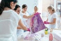 Group of five female creating and slowly whirling canvas with liquid acrylics abstract painting in art therapy class.