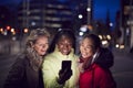 Group Of Female Friends On City Street At Night Ordering Taxi Using Mobile Phone App