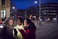 Group Of Female Friends On City Street At Night Ordering Taxi Using Mobile Phone App