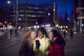 Group Of Female Friends On City Street At Night Ordering Taxi Using Mobile Phone App